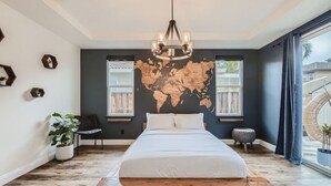 Une chambre dotée d’un grand lit, d’une fresque représentant une carte du monde, d’un luminaire suspendu et offrant une vue sur l’extérieur.