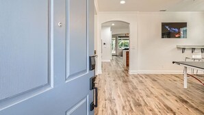 Un intérieur moderne avec un plancher en bois, un coin repas comprenant une table et des chaises, et une cuisine en arrière-plan.