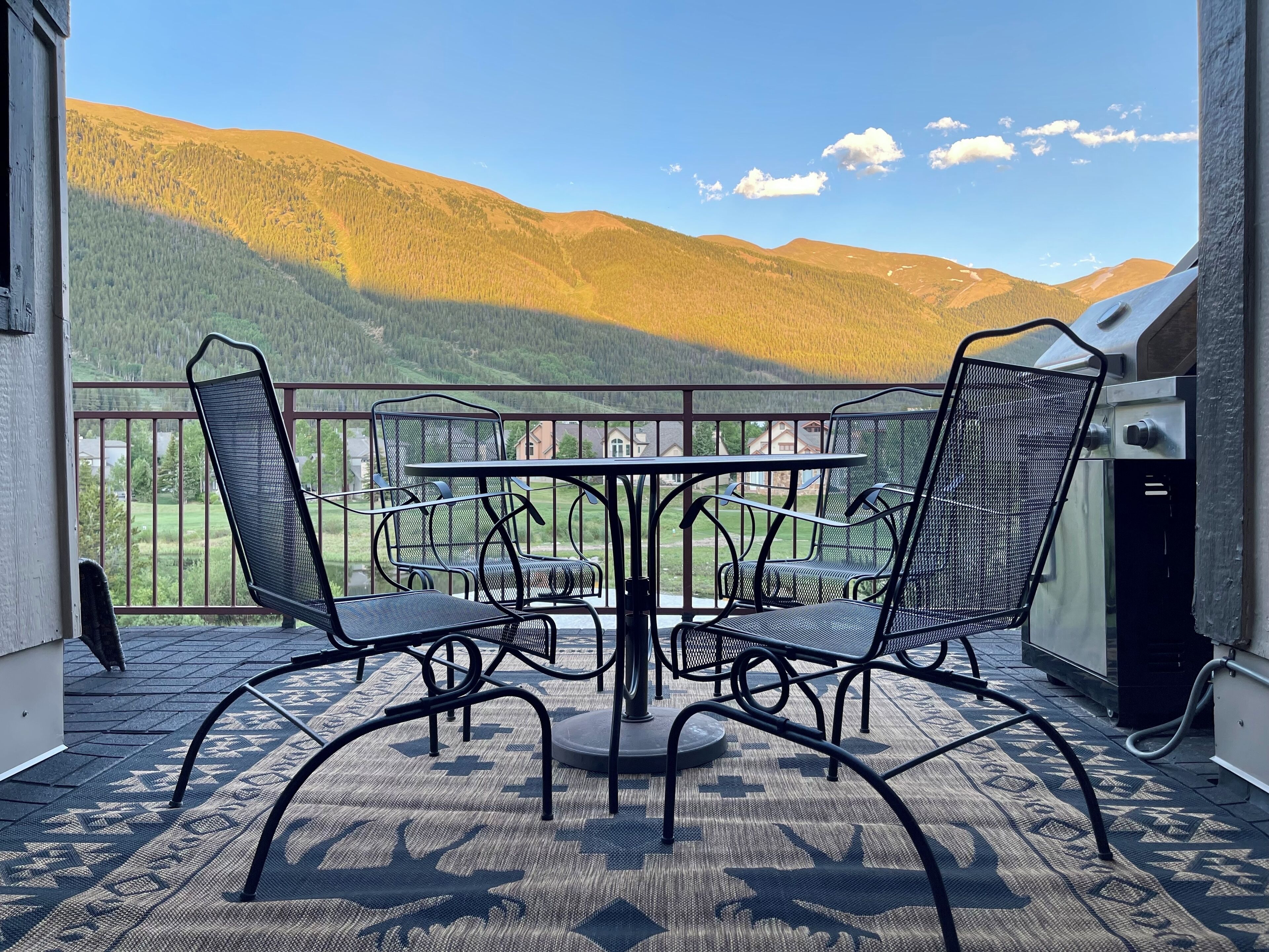 Ein Balkon mit Tisch und Stühlen, mit Blick auf eine gebirgige Landschaft.