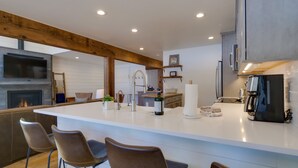 A modern kitchen with a large island, bar stools, a built-in oven, and a coffee machine. - BEST LOCATION! Ski-In Ski-Out - Copper Mt - HotTub, Sleeps 8 (Frisco)