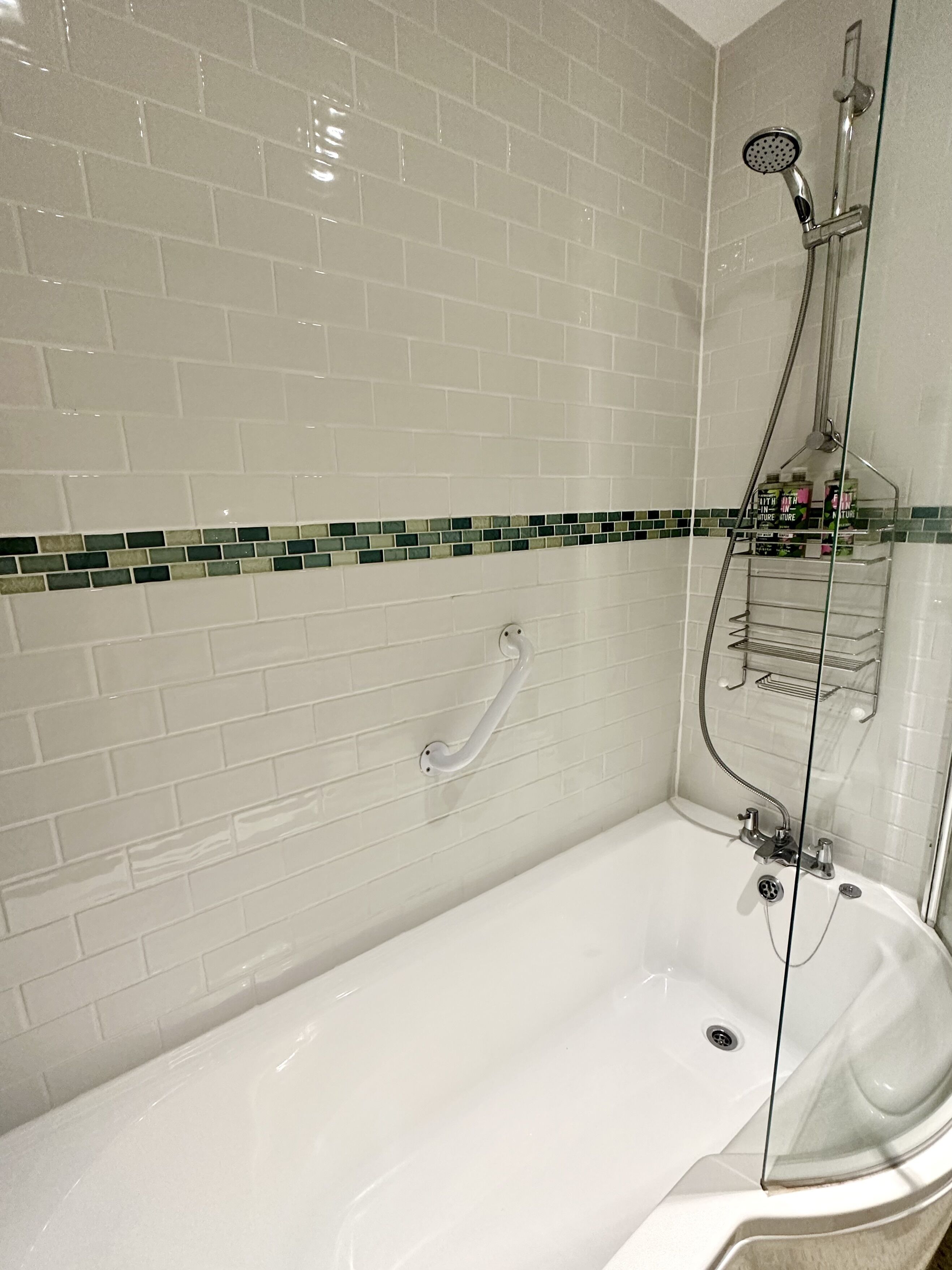 Ein modernes Badezimmer mit einer weißen Badewanne, einer Duschkabine aus Glas und einer Handstange.