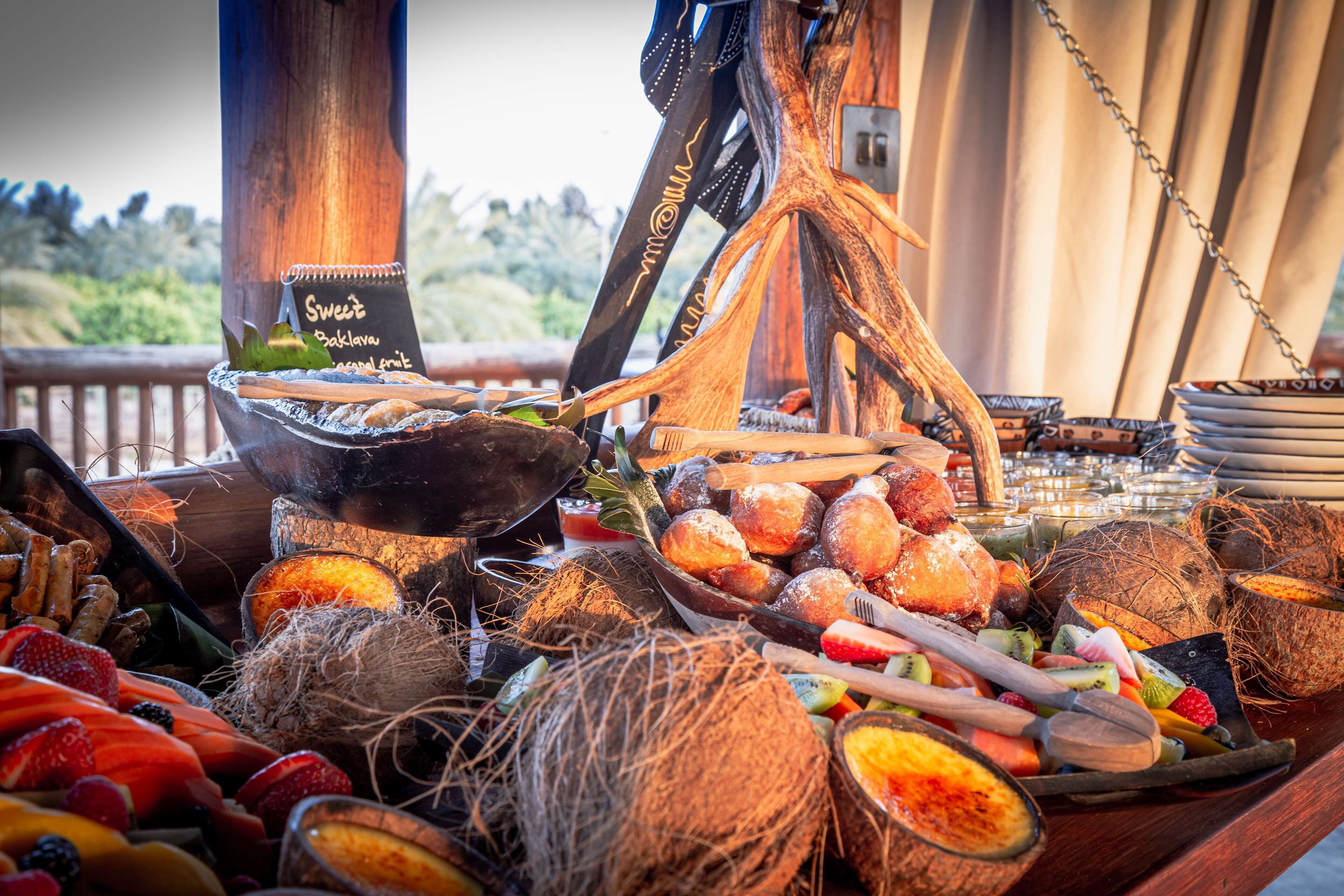 Une table de buffet proposant une variété de fruits, de pâtisseries et de décorations à base de noix de coco.