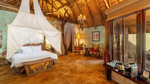 A room with a canopy bed, stone walls, a wooden ceiling, and a breakfast bar with coffee-making equipment.