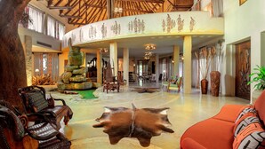 A spacious lobby with a high ceiling, a central seating area, and a decorative wall with indigenous artwork.