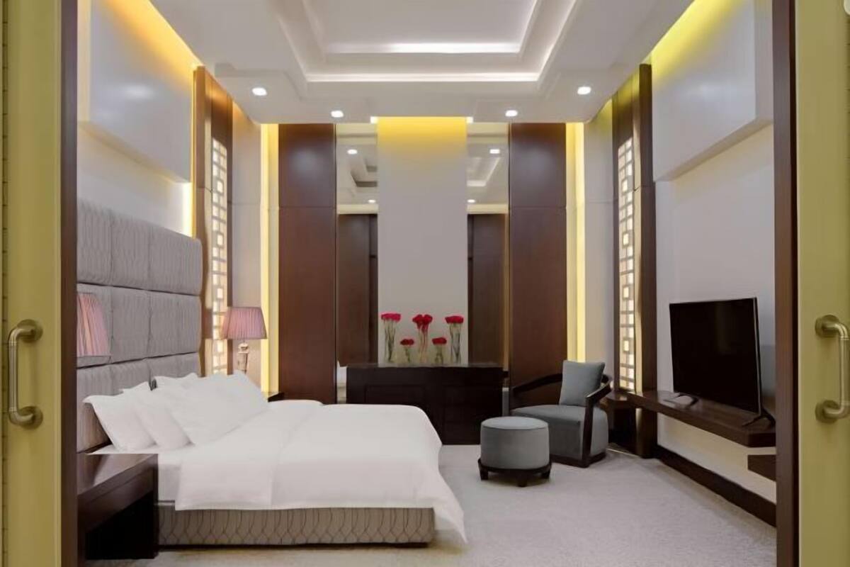 Una habitación de hotel moderna con una cama, televisión, escritorio y una silla.