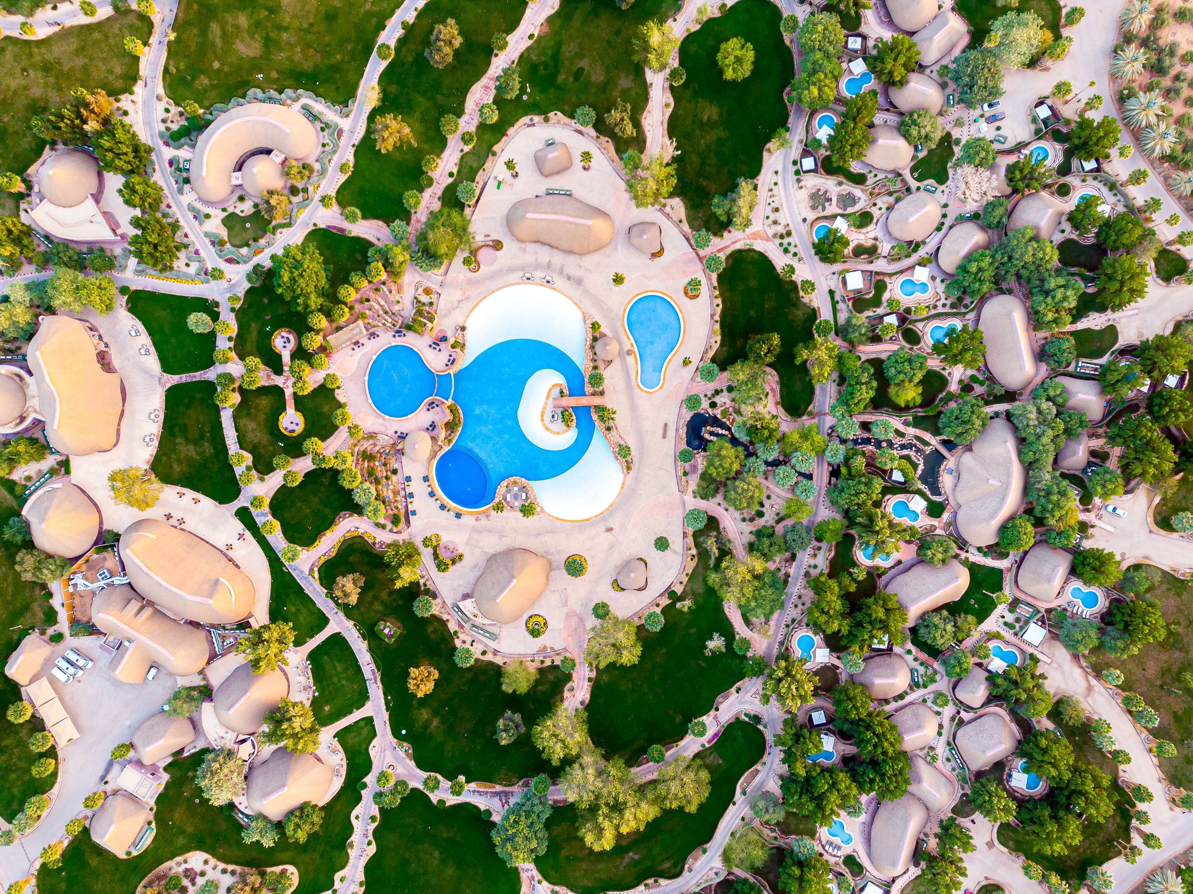 Vue aérienne d’un complexe hôtelier doté de plusieurs piscines, d’espaces paysagers aménagés et de bâtiments à l’architecture originale.