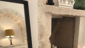 A bedroom with a stone fireplace, a bed with a white bedspread, and a lamp. - TRULLO SUITE 'THE QUEEN' in Itria Valley with swimming pool (Martina Franca)