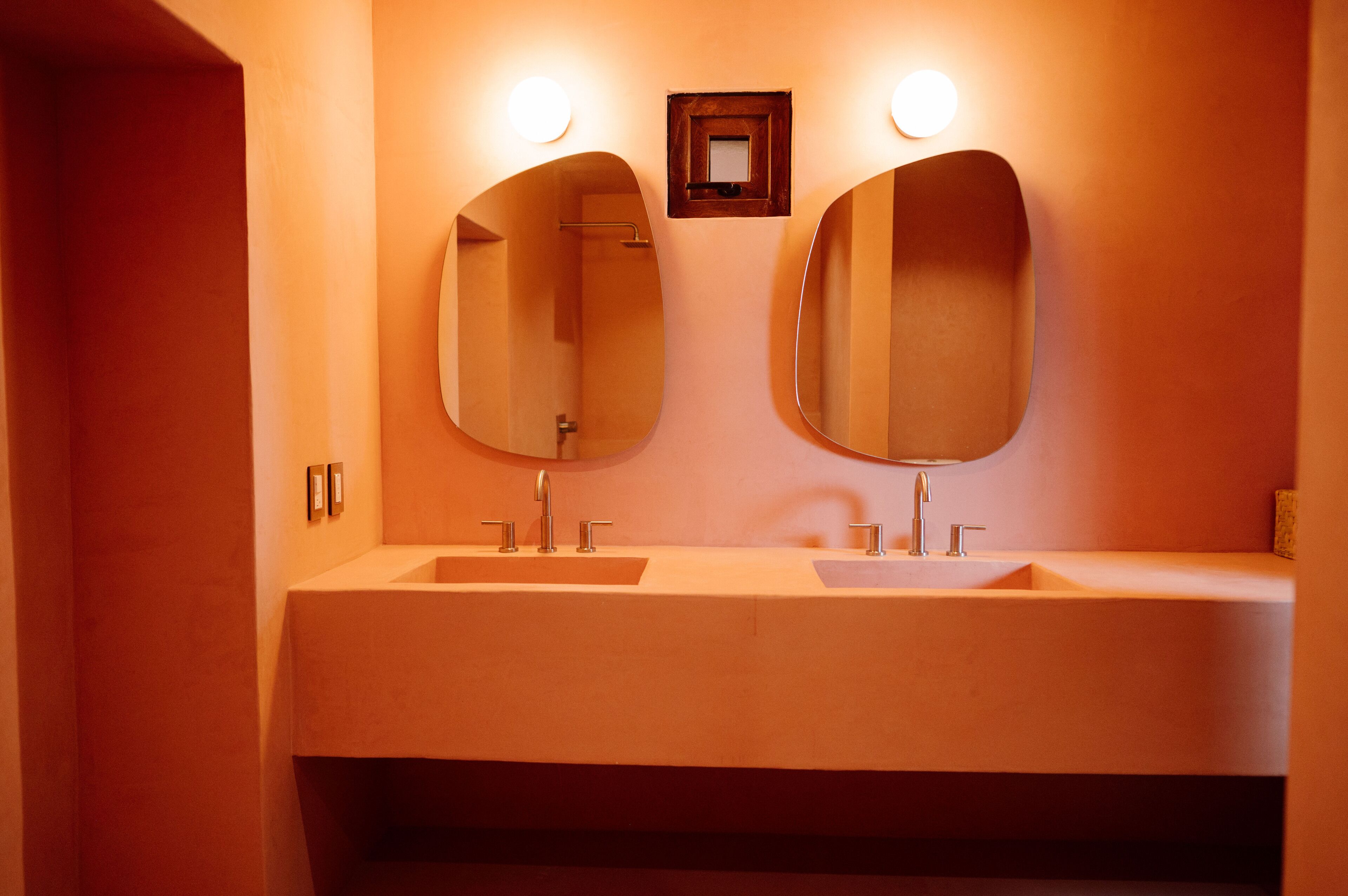 Un baño con dos lavamanos y dos espejos grandes.