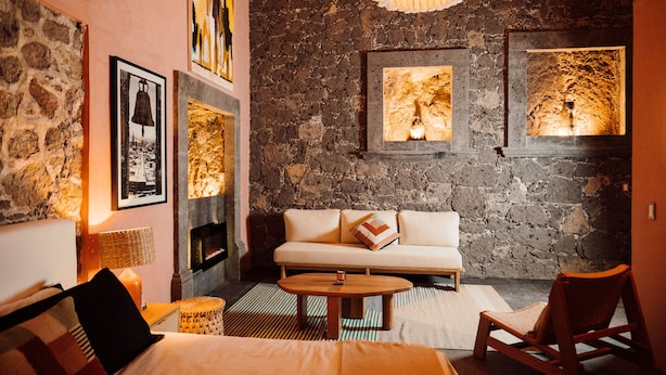 Una habitación acogedora con pared de piedra, un sofá, una mesa de centro de madera y una silla.