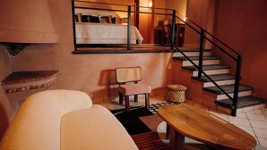 Una habitación de hotel acogedora con una cama, un banco de madera, una silla y una escalera.