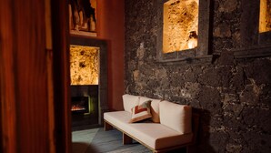 Una habitación acogedora con pared de piedra, un banco de madera y chimenea.