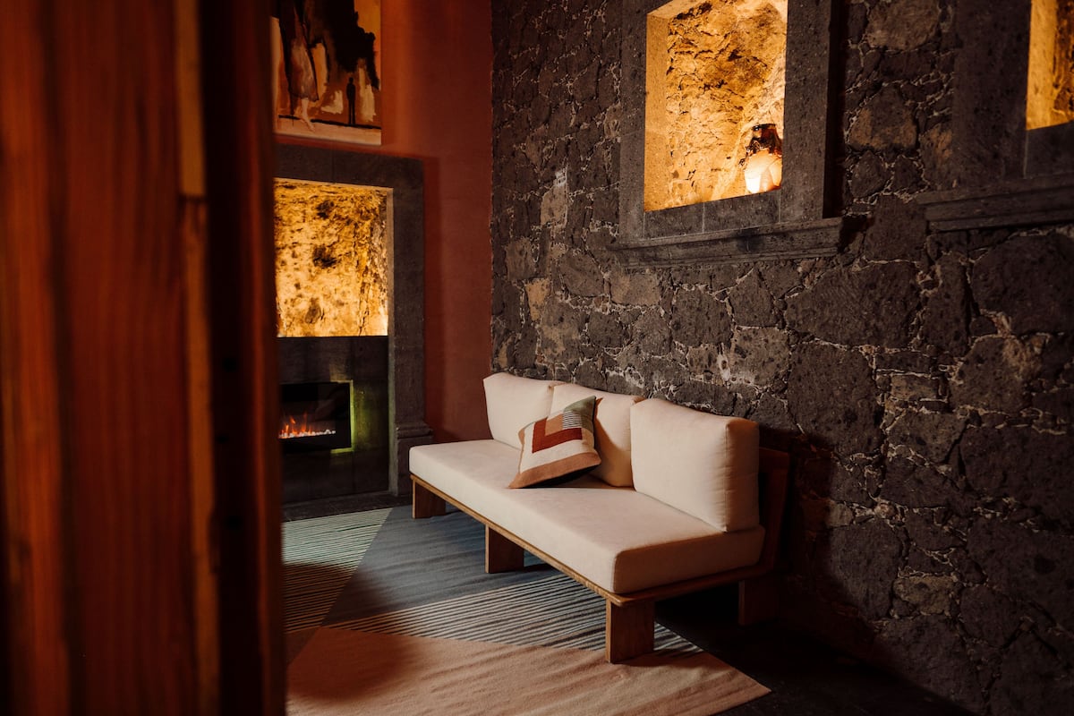 Una habitación acogedora con pared de piedra, un banco de madera y chimenea.