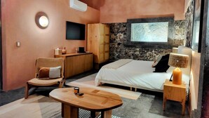 Un dormitorio moderno con cama, mesita de noche, lámpara, silla y televisor.