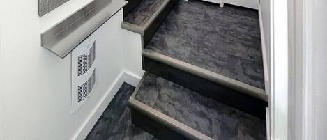 A staircase leading to a second floor with a bulletin board on the wall.