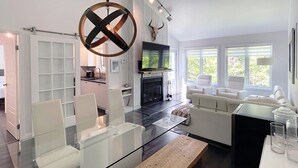 A modern living room with a glass coffee table, white sofas, and a fireplace. - Croissant des Soleils - RVMT (Mont-Tremblant)