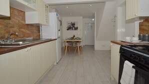 A modern kitchen with white cabinets, a wooden countertop, and a tiled backsplash. - Charming 5-bed House in City Center and Car Park (Birmingham)