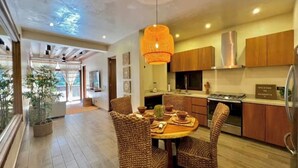 A modern kitchen with wooden cabinets, a dining area with wicker chairs, and a large window. - Beautiful apartment with pool (Sayulita)
