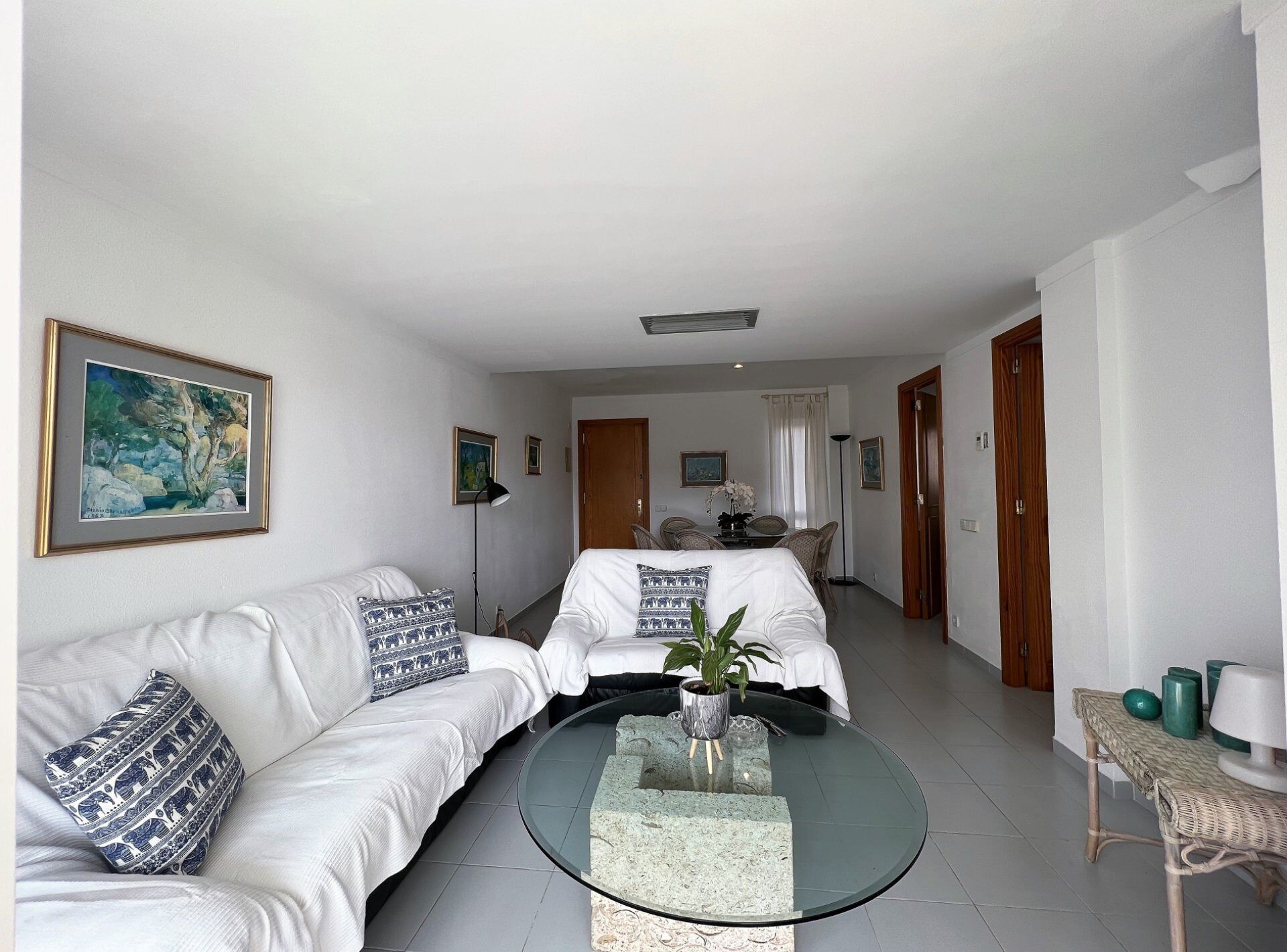 Une chambre d’hôtel avec un lit, un canapé, une table basse en verre et un tableau au mur.