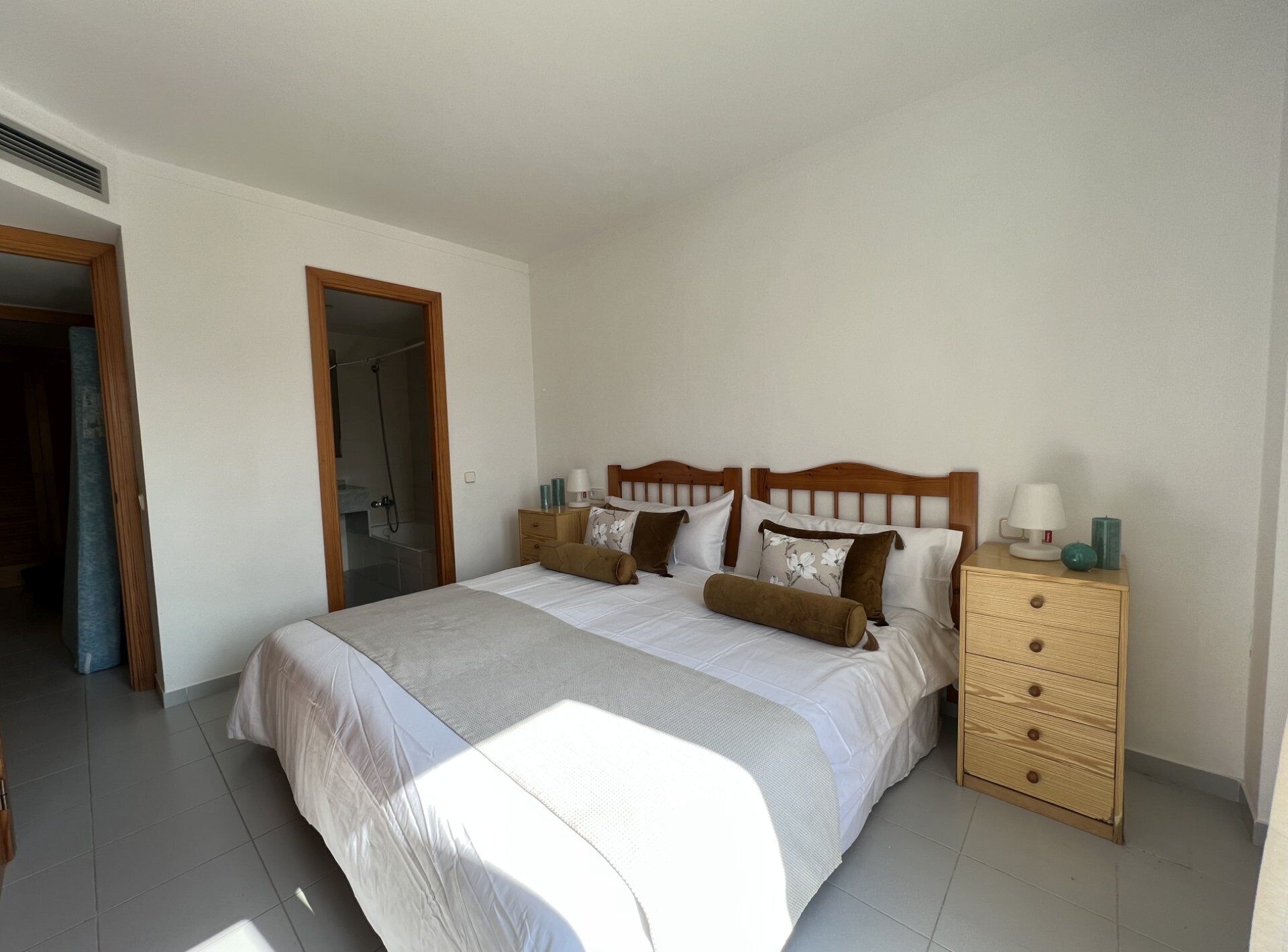 Une chambre à coucher avec un grand lit, une tête de lit en bois, des tables de chevet et une armoire.