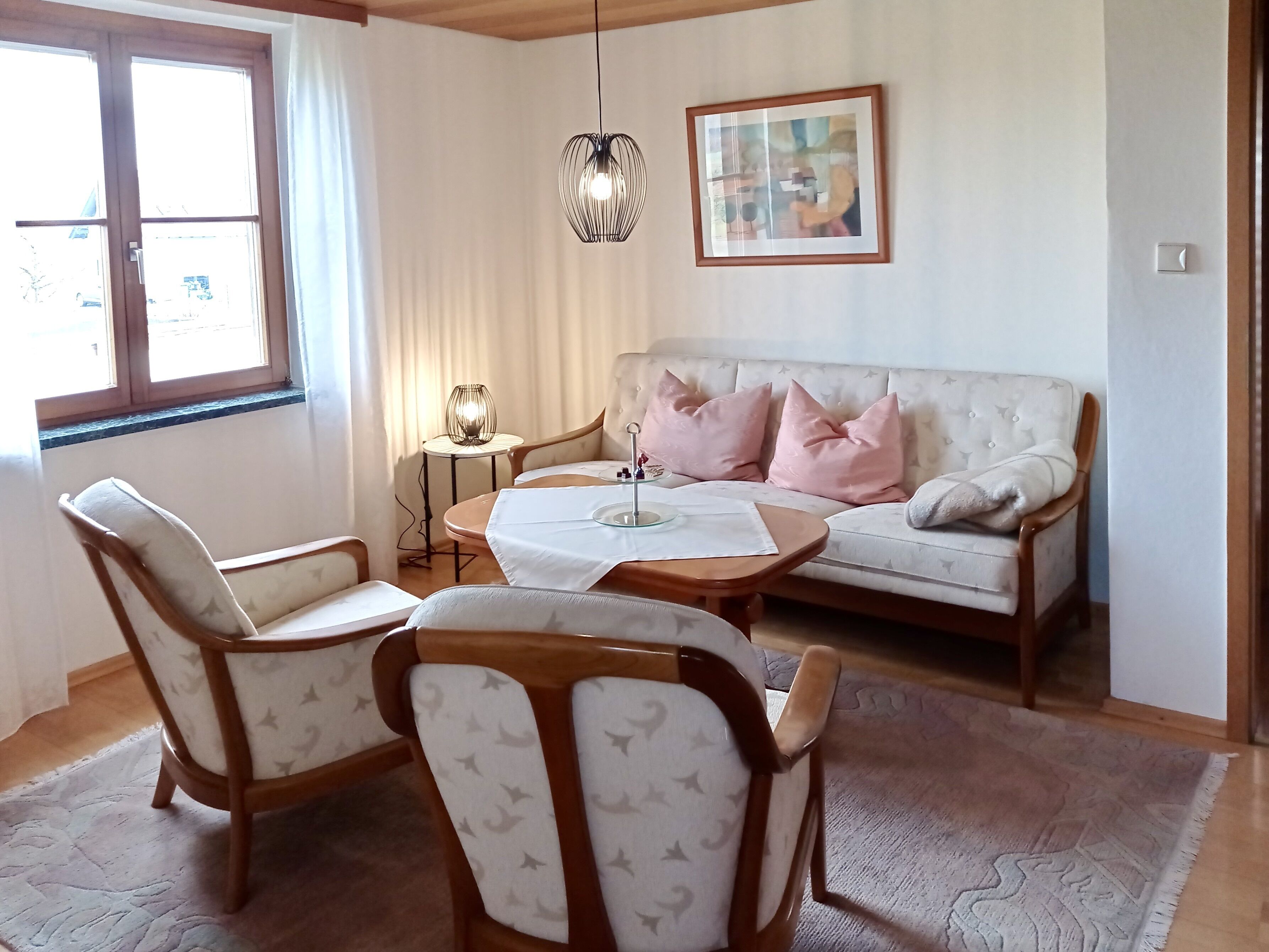A living room with a sofa, two armchairs, a coffee table, a lamp, and a framed picture on the wall.