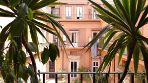 Un edificio de varios pisos con balcones, rodeado de exuberante vegetación.