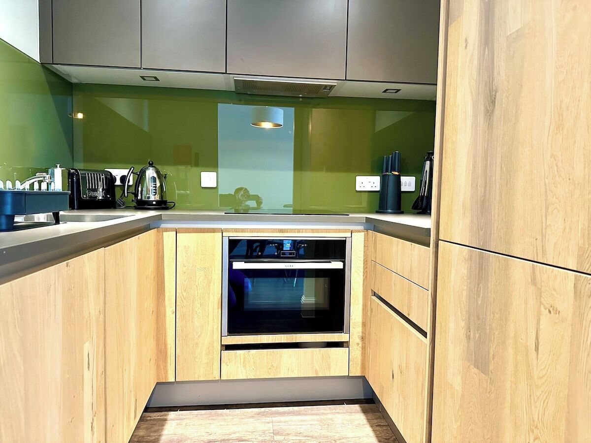 Une cuisine compacte avec des meubles en bois, un four encastré et un plan de travail équipé de divers appareils.