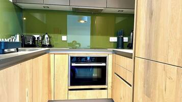 Une cuisine compacte avec des meubles en bois, un four encastré et un plan de travail équipé de divers appareils.