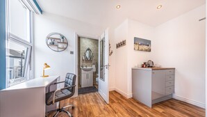 Een moderne kantoorruimte met een bureau, stoel en een kleine kitchenette.