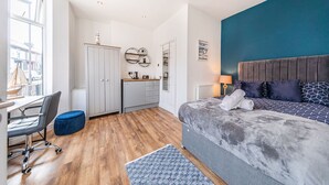 Een moderne slaapkamer met een groot bed, een bureau en een kledingkast.