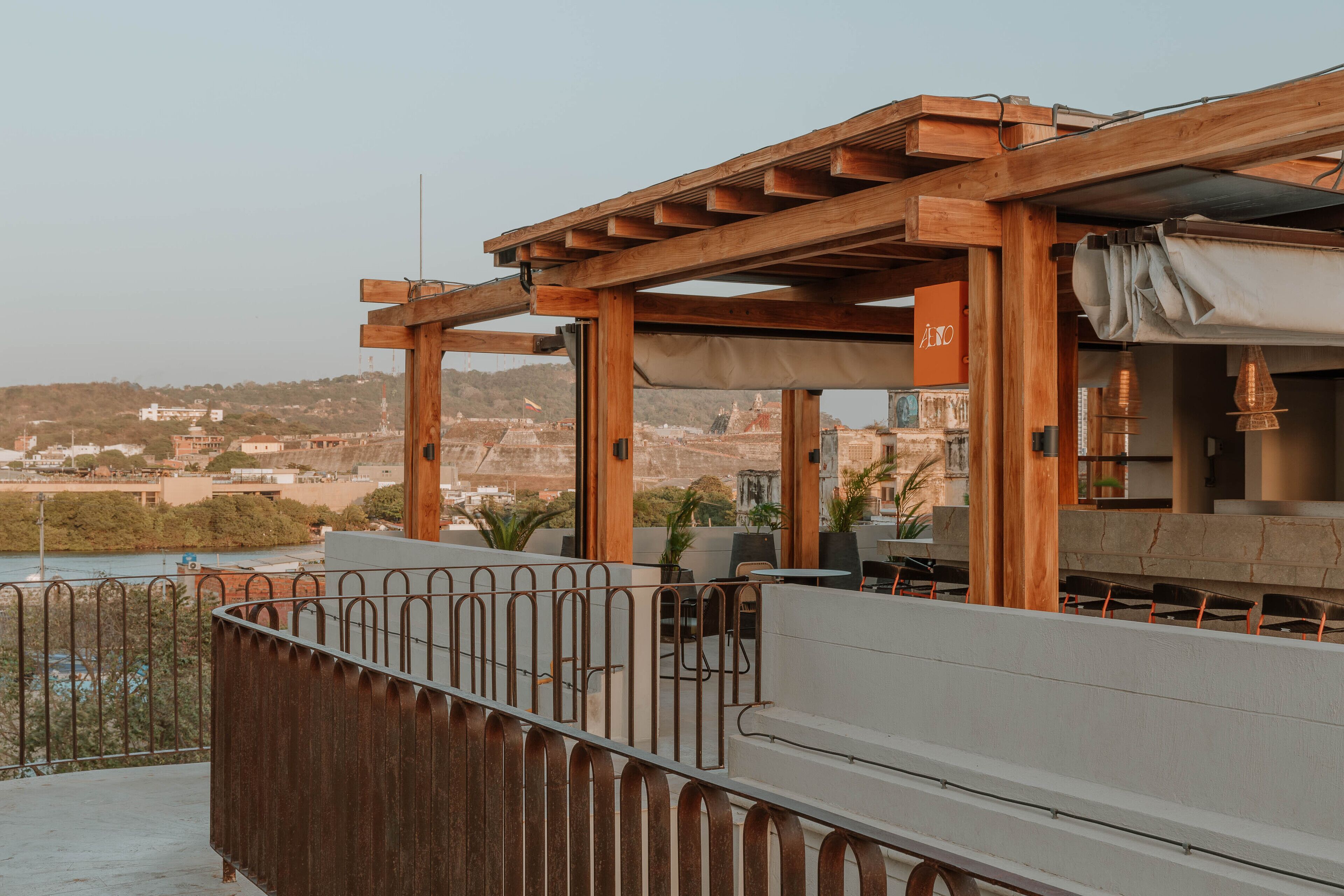 A rooftop terrace with wooden pergolas, seating areas, and a view of the cityscape.