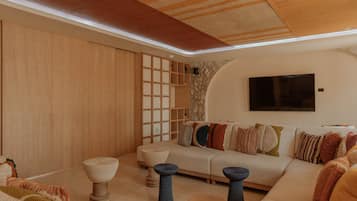 Een moderne woonkamer met een bank, salontafel en decoratieve krukken.