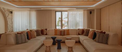 A modern living room with a sectional sofa, two coffee tables, and a large window with curtains.