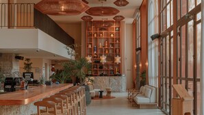 Un hall d’hôtel spacieux avec un long bar, un coin salon et une grande bibliothèque remplie d’objets décoratifs.
