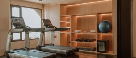 A modern gym with treadmills, a rowing machine, and a small exercise ball.