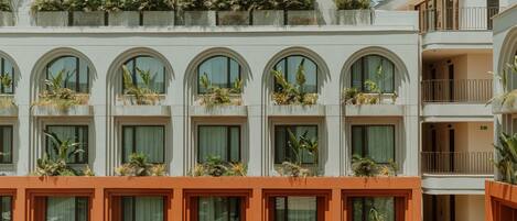 A hotel with multiple balconies, each with plants and a view of the sky.