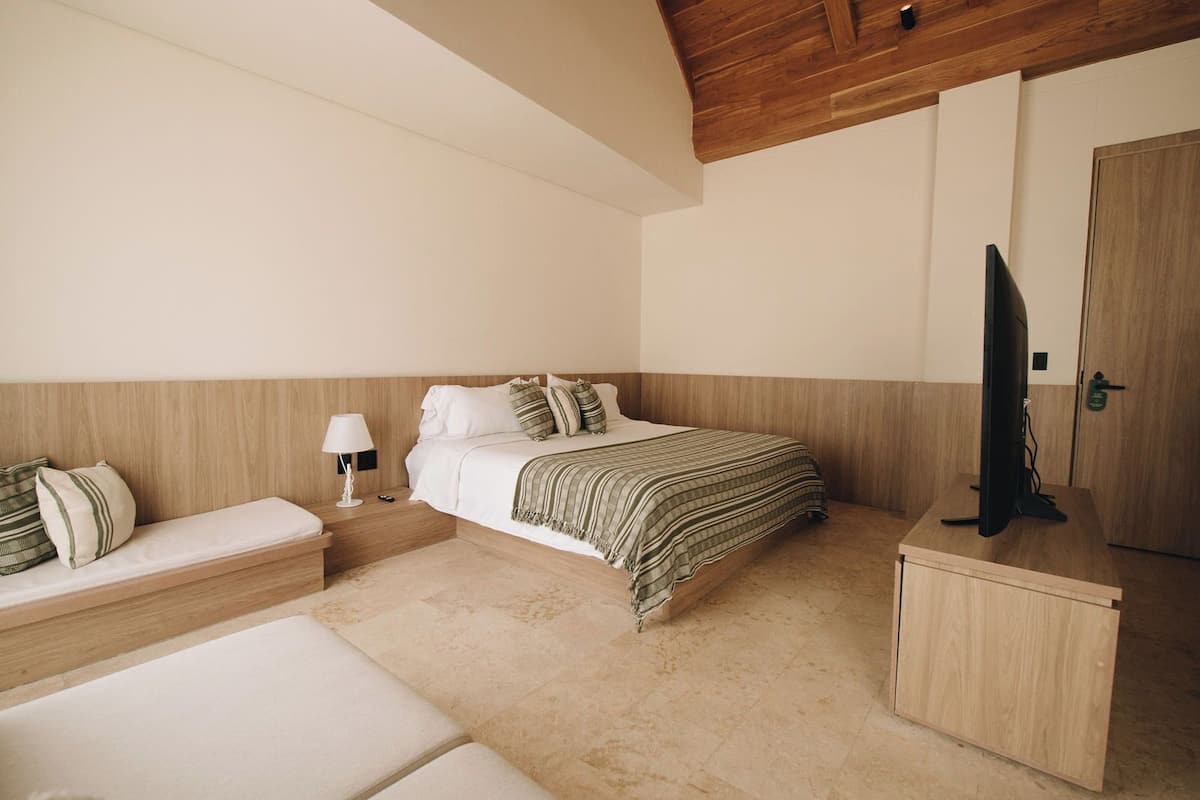 A bedroom with a bed, bedside table, lamp, TV, and a small cabinet.