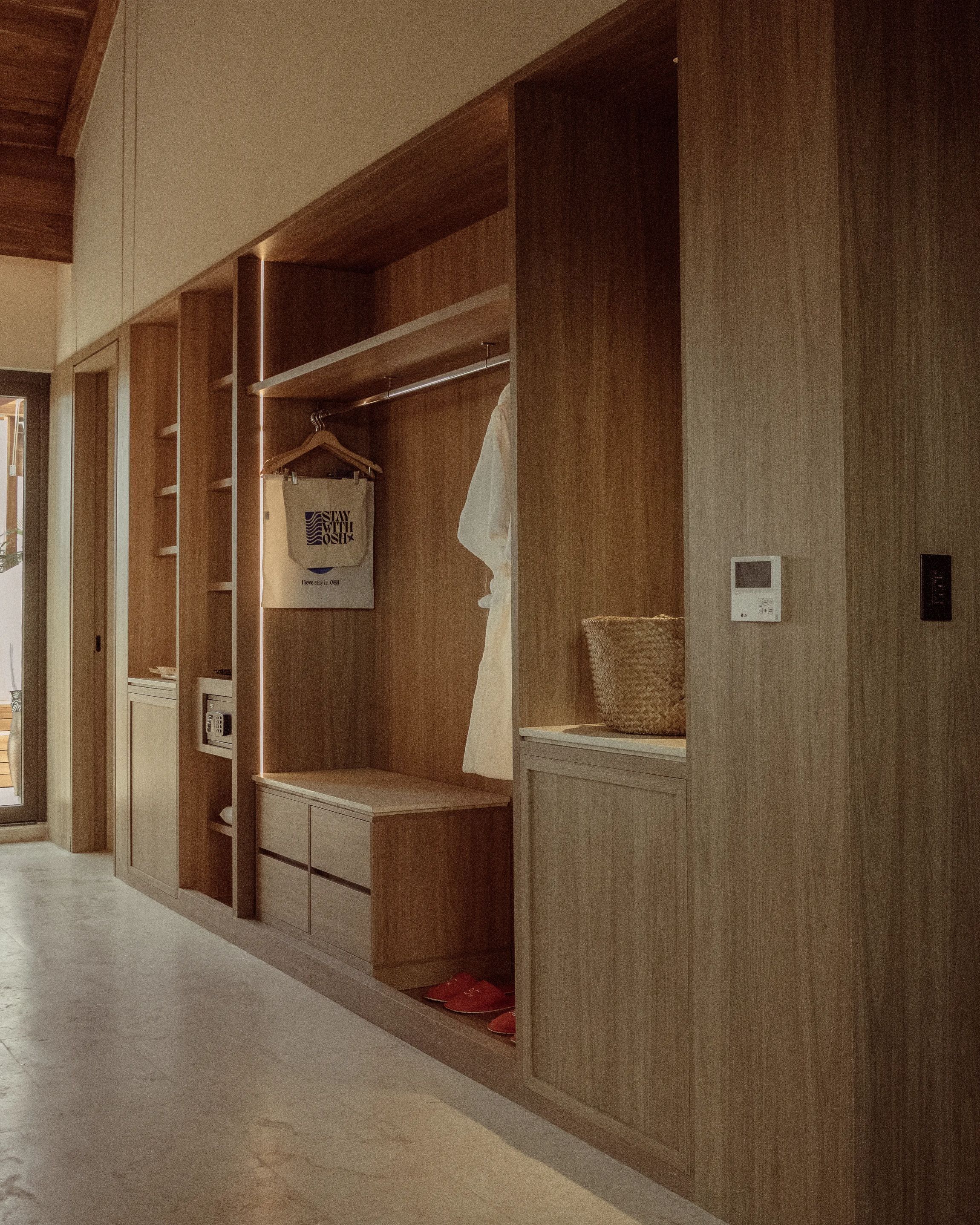 Habitación de hotel con paneles de madera, una cama, armario con espacio para colgar, microondas y termostato.