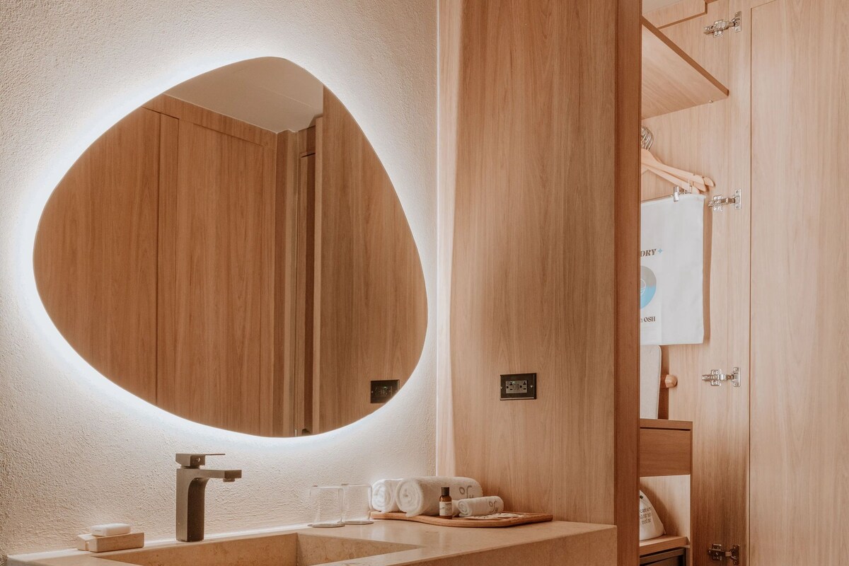 A modern bathroom with a wooden vanity, a large mirror, and a built-in shower.