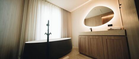 A modern bathroom with a freestanding bathtub, a wooden vanity, and a large mirror.
