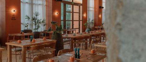 A restaurant with wooden tables and chairs, potted plants, and a sign indicating a smoking area.