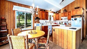 Une cuisine avec des meubles en bois, un îlot central et un coin repas avec des chaises.