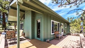 Une maison en bois peinte en vert, dotée d’un porche abrité, d’une petite terrasse et de mobilier d’extérieur.