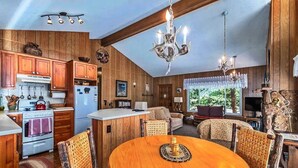 Une cuisine rustique avec des meubles de rangement en bois, une table à manger et un lustre.
