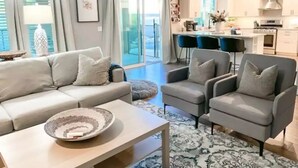 A modern living room with a sofa, armchairs, and a coffee table. There is a kitchen in the background with a dining area. - Fantastic Family Fun 5BR w Pool/Spa in Gilbert (Gilbert)