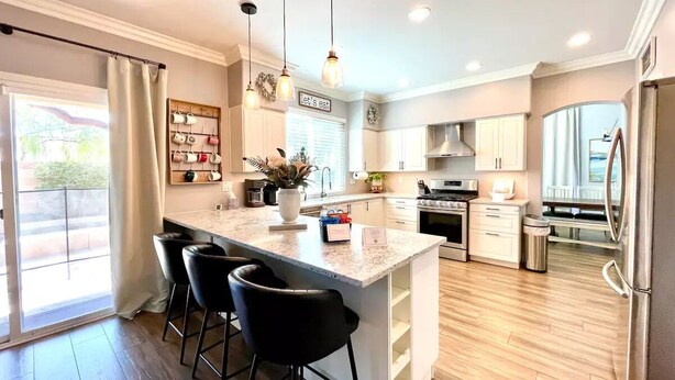A modern kitchen with a central island, bar stools, pendant lighting, and a view to the outside. - Fantastic Family Fun 5BR w Pool/Spa in Gilbert (Gilbert)