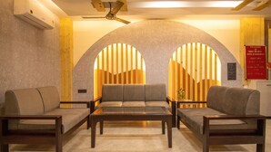 A modern hotel lobby with a sofa set, a coffee table, and a reception desk. - Holy Shivana Boutique Hotel Rishikesh (Narendranagar)