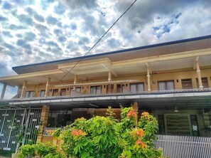 A two-story building with a flat roof and a balcony on the upper floor.