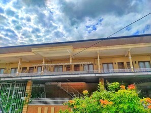 A multi-story building with a flat roof, balconies, and a covered walkway.