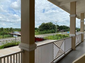A balcony with a view of a road, greenery, and a cloudy sky. - Putih Salju Homestay Syariah (Indralaya)