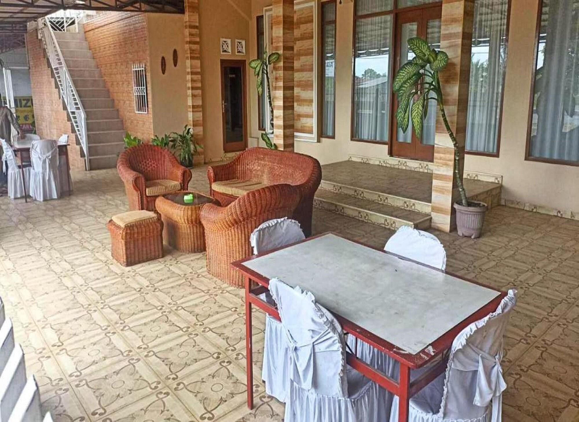 A covered outdoor seating area with wicker furniture, a table, and potted plants.
